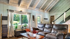 A living room with a brown leather sofa, a wooden coffee table, and a window with curtains.