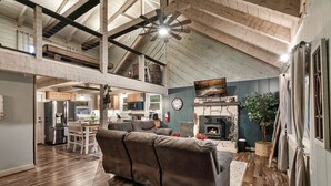A spacious loft-style living area with a high ceiling, exposed beams, and a fireplace.
