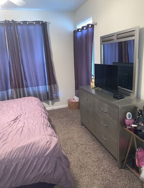 Cozy retreat with a comfortable bed, dresser, and TV, perfect for a restful stay.