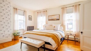 A bedroom with a bed, a bench, a small table, and a potted plant. - Spacious West End Retreat, 3BR/2BA, Walk Everywhere + Private Deck (Portland)