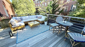 A deck with a sofa, chairs, a table, and a patterned rug.