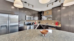 A modern kitchen with granite countertops, stainless steel appliances, and dark wooden cabinets.