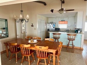 A dining area with a wooden table and chairs, a chandelier, and a ceiling fan.