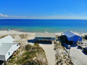 A beachside property with a large house, a smaller building, and a boat.