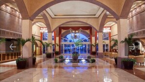 Un hall d’entrée spacieux avec une fontaine centrale, des plafonds en arc de cercle et des plantes en pot.