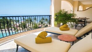 Un balcon avec deux fauteuils de couleur beige, une petite table ronde et un pot de fleurs.