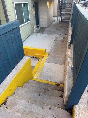 A concrete pathway with yellow and blue painted edges, leading to a building entrance. - Entire Apartment Suite (Austin)