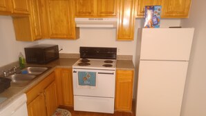 A kitchen with wooden cabinets, a microwave, stove, and a refrigerator.