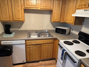 A kitchen with wooden cabinets, a dishwasher, a microwave, and a stove.