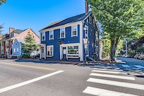 A two-story building with a blue facade, a visible storefront, and a crosswalk in front.