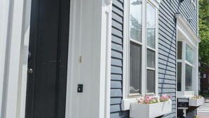 Ein Haus mit dunklem Eingangstür, weißer Fassade und einem Fenster mit Blumenkasten.