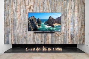 A flat-screen TV mounted on a marble wall with a fireplace below.