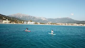A coastal area with two paddleboarders on the water.
