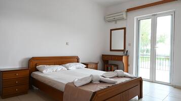 A bedroom with a wooden bed, a nightstand, a dresser, a mirror, and a sliding glass door to a balcony.