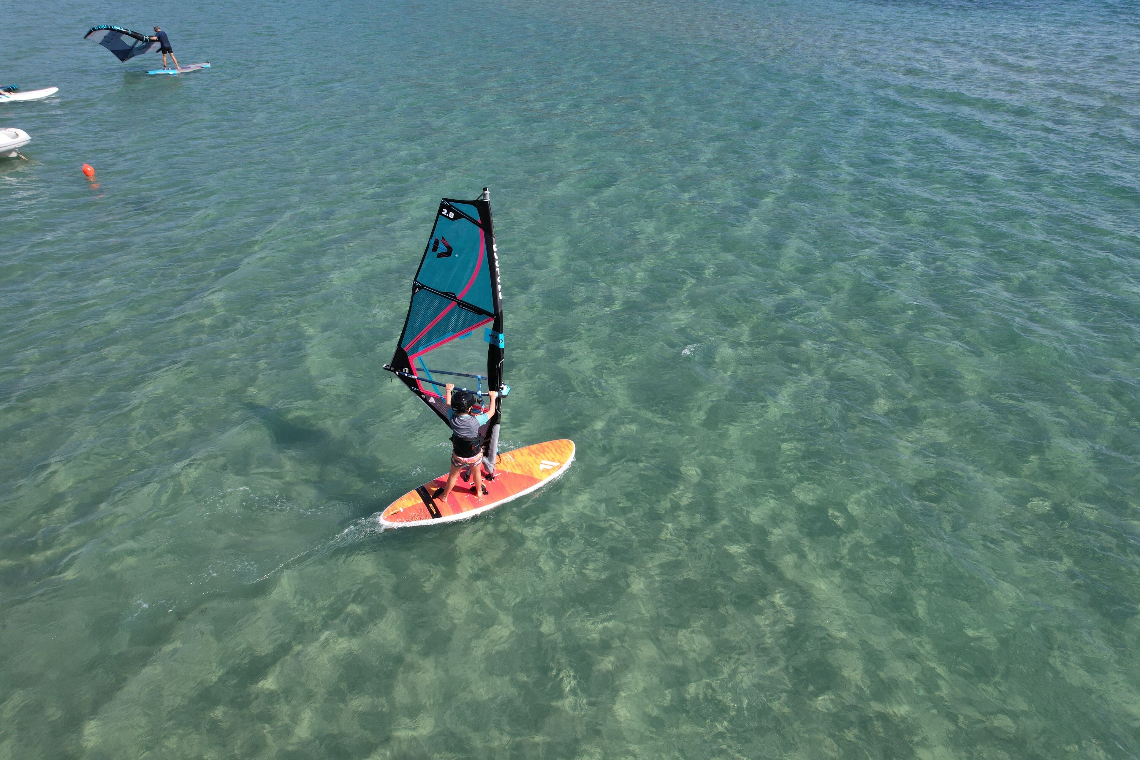 A person windsurfing in clear water.