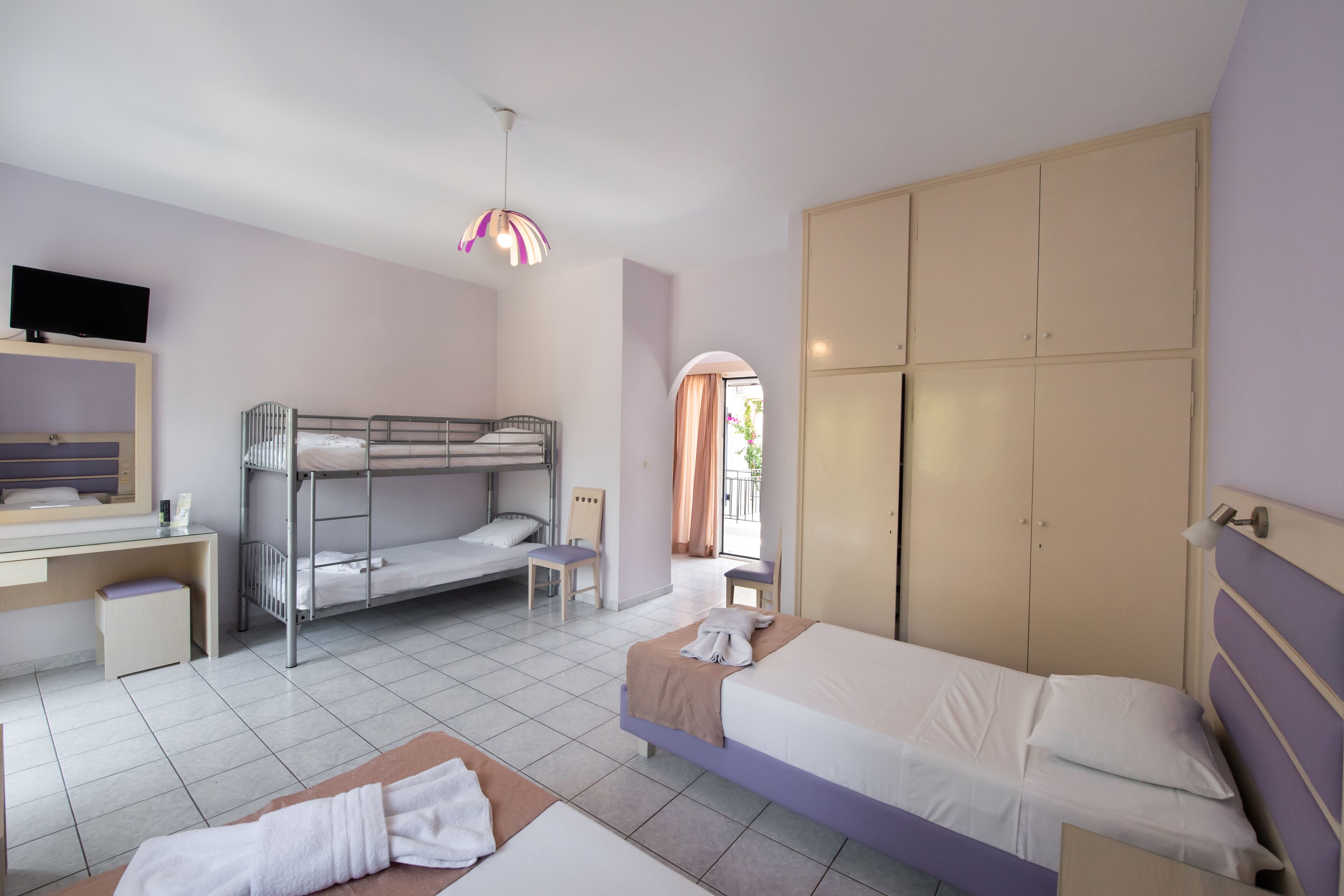 A bedroom with bunk beds, a desk, a chair, a wardrobe, and a television.