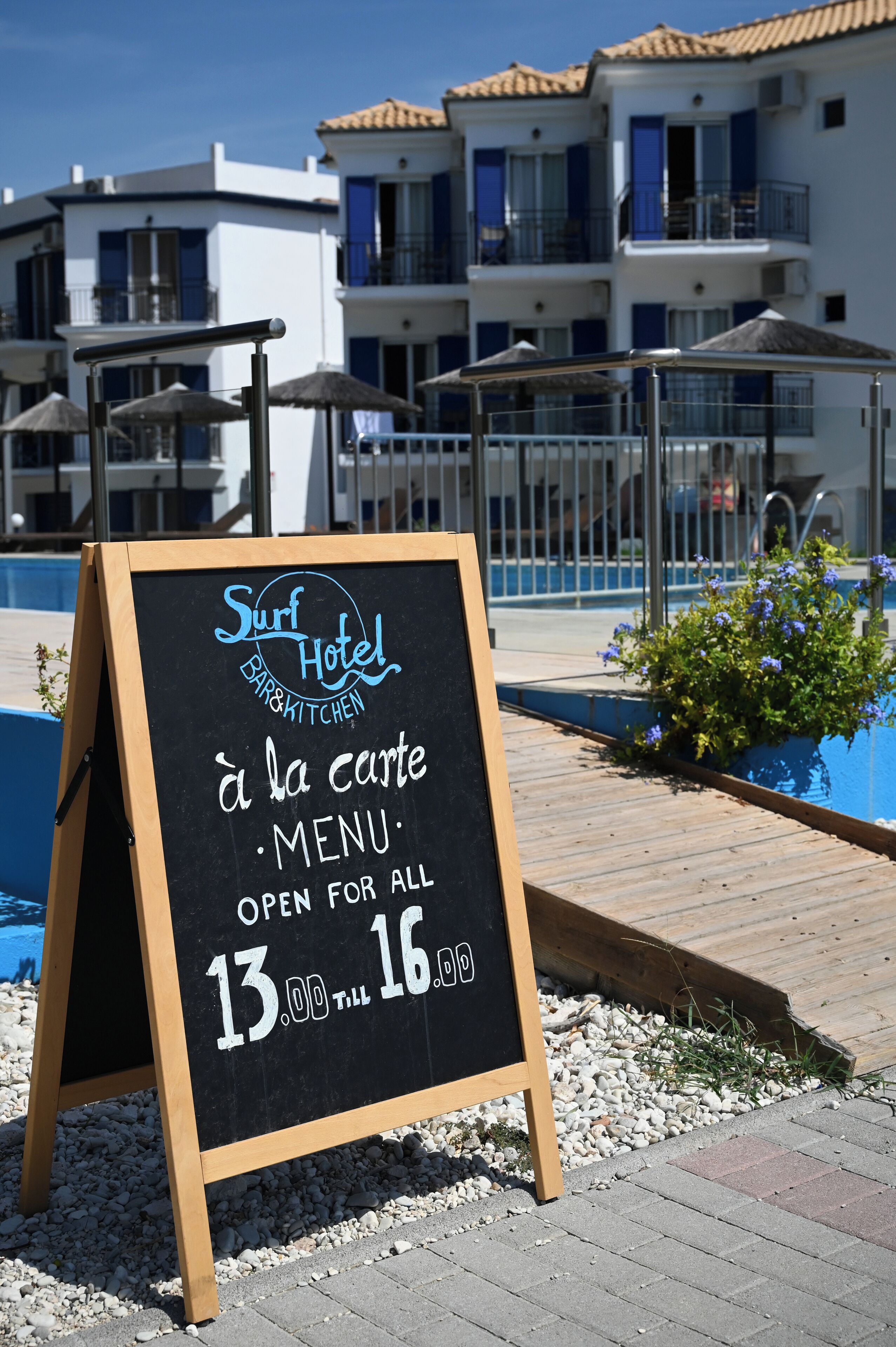 A blackboard sign for Surf Hotel Bar & Kitchen with a menu open for all, priced between 13.00 and 16.00.