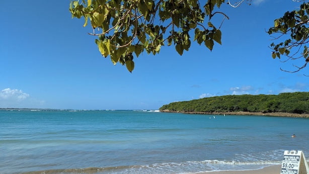 A beach with clear blue water, a sandy shore, and a sign advertising rental services. - Beautiful Villa with Golf Course, Ocean, and Rainforest Views. (Rio Grande)