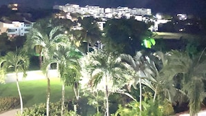 A nighttime view of a resort with multiple buildings, palm trees, and a well-lit pathway. - Beautiful Villa with Golf Course, Ocean, and Rainforest Views. (Rio Grande)