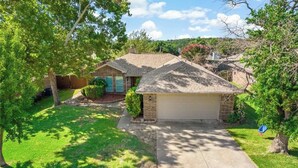 A single-story house with a garage, surrounded by a well-maintained lawn and trees. - Close to everything and quiet for peace (Euless)