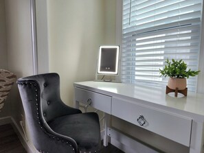 Un escritorio moderno con un monitor de computadora, una silla y una planta en maceta.
