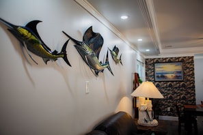A room with a wall-mounted fish sculpture, a lamp, and a painting.