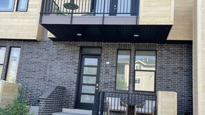 A modern two-story building with a balcony, a black door, and a brick facade.