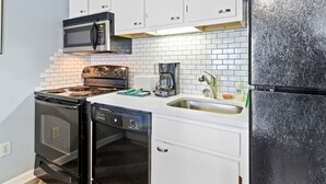 A kitchen with white cabinets, a black refrigerator, a microwave, a coffee maker, and a dishwasher. - ML204 Chairlift View Near Village WiFi EZ Parking (Dunmore)