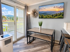 Une cuisine moderne avec une table en bois, une plante en pot et une grande fenêtre donnant sur un paysage magnifique.