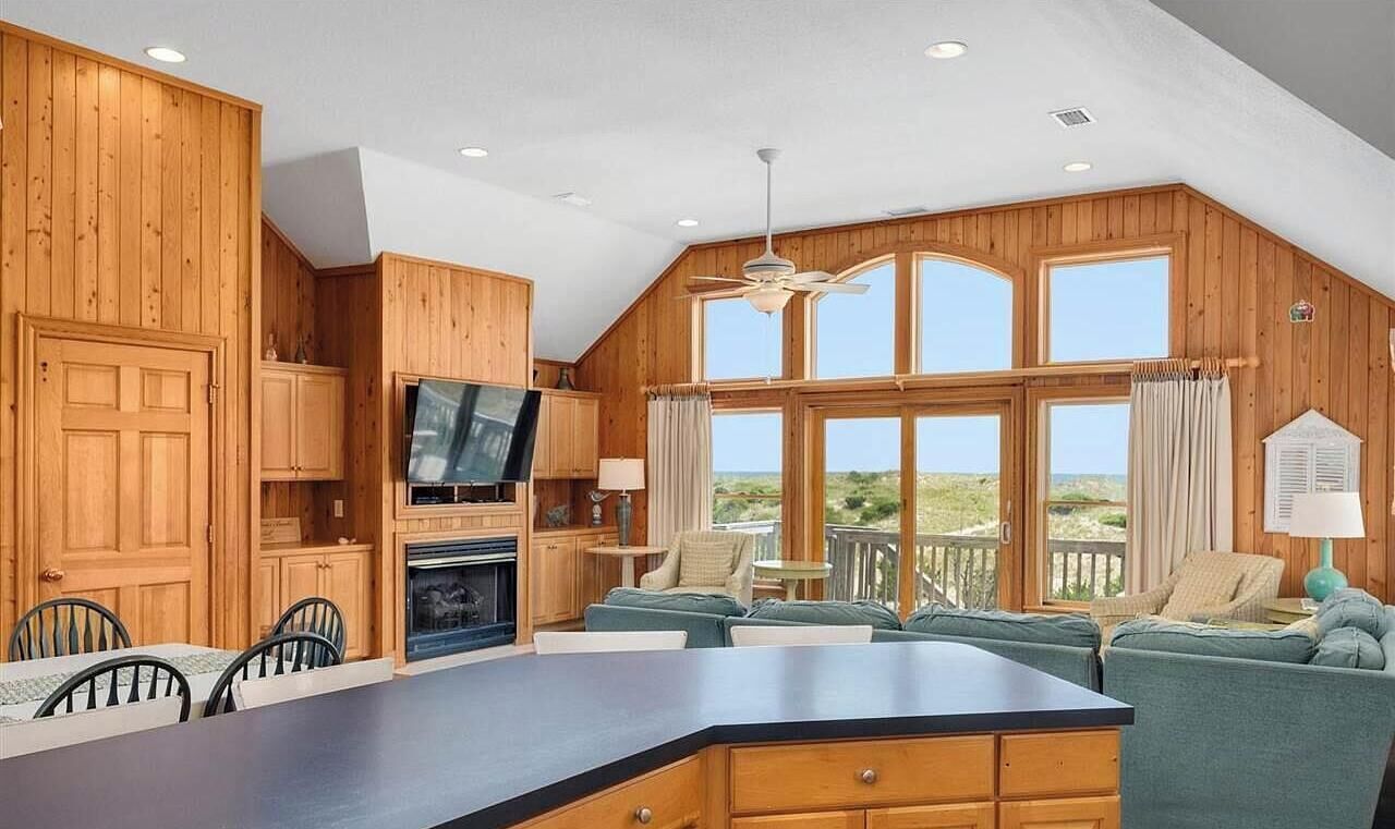 A spacious kitchen with wooden cabinets, a large island, and a television.