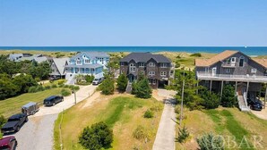 A coastal residential area with houses, a clear sky, and a view of the ocean. - Oceanfront, Pet- & Handicap- Friendly Home w/ Heated Pool, Elevator & Game Room (Salvo)