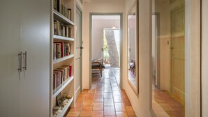 A hallway with a bookshelf, a door, and a view into another room.