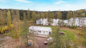 A cabin with a metal roof, surrounded by trees and a lake. - Stunning home in Svanskog with sauna (Svanskog)