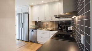 A modern kitchen with stainless steel appliances, white cabinetry, and a black tiled backsplash. - Stunning home in Svanskog with sauna (Svanskog)