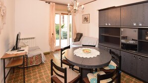 A dining area with a round table, chairs, a chandelier, a cabinet with shelves, and a radiator. - 2 bedroom lovely apartment in Chatillon (Chatillon)