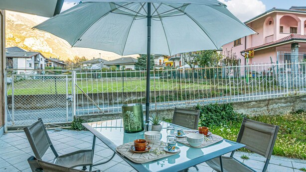 An outdoor patio with a table set for two, a large umbrella, and a view of a residential area with houses and a fence. - 2 bedroom lovely apartment in Chatillon (Chatillon)