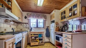 Cocina compacta con armarios de madera, horno empotrado, microondas y cafetera.