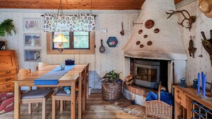 Una habitación acogedora con techo de madera, una mesa de comedor con sillas, chimenea y varios adornos en las paredes.