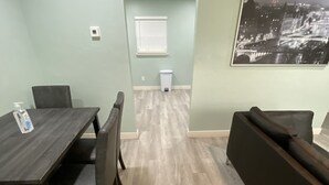 Ein Essbereich mit einem Holztisch und Stühlen, einer Couch und einem Mülleimer.