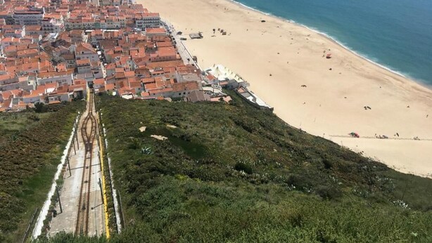 Un pueblo costero con playa, vías de tren y edificios residenciales.