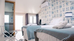 Habitación de hotel con dos camas, un tendedero, un ventanal grande e ilustraciones de vida marina en la pared.