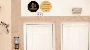Dos puertas blancas con un cartel con el número 22 en la parte superior, una luz de pared y una placa con un símbolo de cruz.
