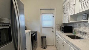 Una cocina compacta con refrigerador, microondas y lavamanos.