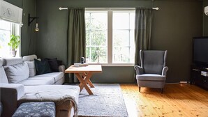A living room with a grey sofa, a wooden coffee table, a grey armchair, and a television on a wooden stand. - 2 bedroom cozy home in Tysse (Tysse)