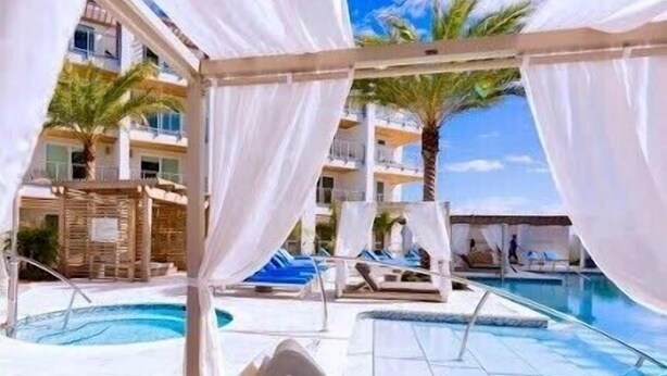 Un espace aménagé au bord de la piscine, doté de parasols blancs, de chaises longues et offrant une vue dégagée sur la piscine.