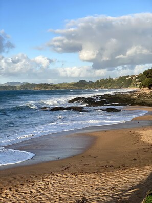 A beach with waves, a clear sky, and distant hills. - Belvedere Amazing views (Cable Bay)