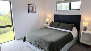 A bedroom with a bed, two bedside tables, a window, and a picture on the wall. - Belvedere Amazing views   (Cable Bay)