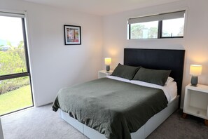 Ein Schlafzimmer mit einem Bett, zwei Nachttischen, einem Fenster und einem Bild an der Wand.