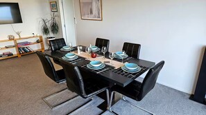 A dining area with a black table set for four, surrounded by black chairs. - Belvedere Amazing views (Cable Bay)