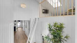 A spacious loft with a wooden staircase, a mezzanine level with a TV, and a large bamboo plant. - Lovely home in Haderslev (Haderslev)